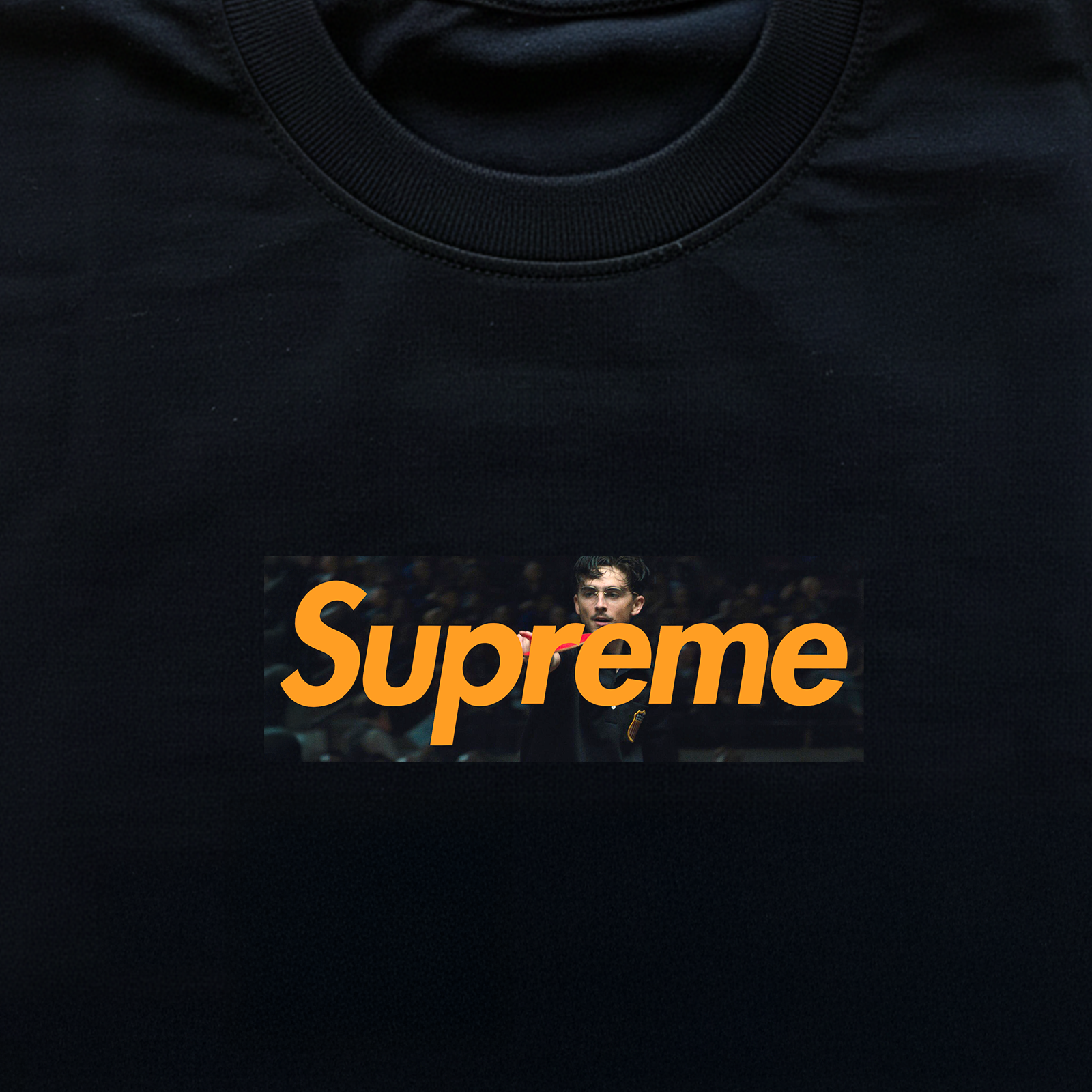 Black t-shirt with 'Supreme' logo featuring a person's face in a box on a black background