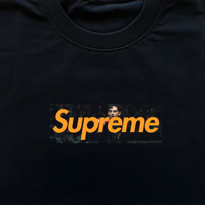 Black t-shirt with 'Supreme' logo featuring a person's face in a box on a black background